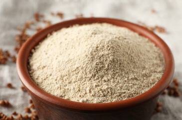 Bowl of buckwheat flour on cloth, closeup