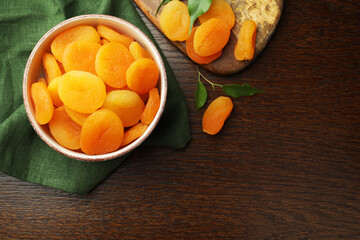 Naklejka na ściany i meble Tasty apricots with green leaves and space for text on wooden table, flat lay. Dried fruits