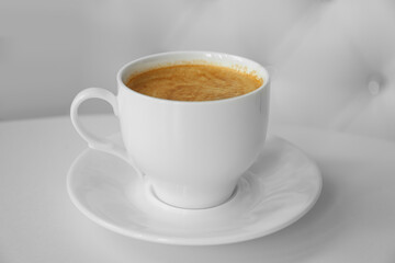 Cup of delicious aromatic coffee on white table indoors, closeup