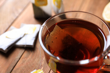 Tea bag in glass cup on wooden table, closeup