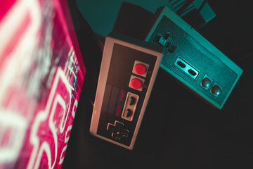 A close up of a retro console and retro controllers in retro 80s environment with colors at night...