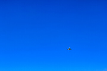 Airplane flies past clear blue sky in Germany.