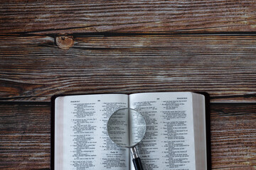 Holy Bible Book and magnifying glass on wooden background with copy space. Top table view....