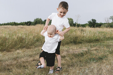 Two playful caucasian brother children enjoy having fun playing together at green grass lawn summer...