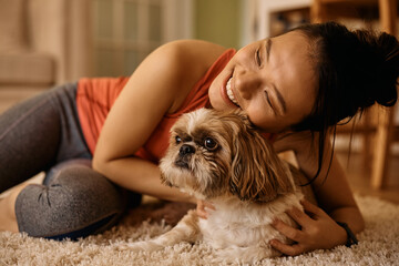 Young happy Asian woman enjoying with her dog at home.
