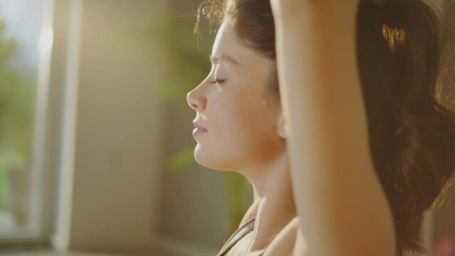 Close-up view of pregnant woman stretching and exercising while standing on yoga mat at modern apartment