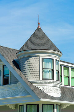 House spire or turret with beige timber or wood slatted exterior with round roof and spike on top on double gable house