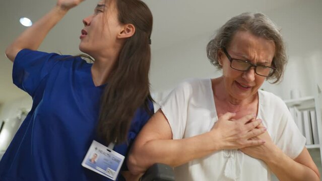 Asian caregiver saving senior woman having chest pain from heart attack.