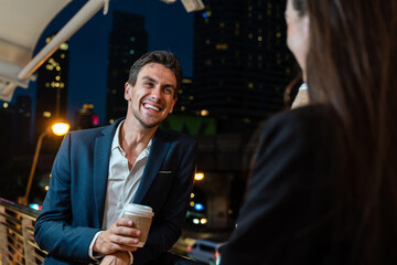 Caucasian young businessman and woman stand outdoor in city at night. 