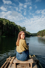 Fototapeta premium Asian woman smile and sitting on a bamboo raft in the lake in the morning, relaxing, People freedom style.
