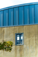 Round roof buildng with blue metal grate accent exterior and smooth cement walls with a tiny window in the shade © Aaron
