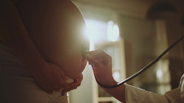 Close-up view of a doctor checking young pregnant women�s abdomen with stethoscope at hospital