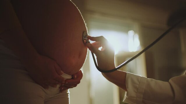Close-up view of a doctor checking young pregnant women�s stomach with stethoscope at hospital