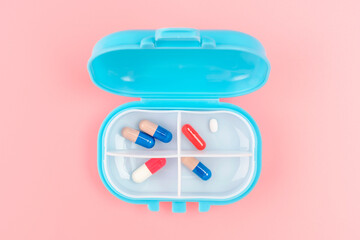 Plastic box pills close-up on a pink background top view.