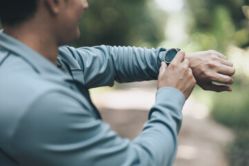 sport man checking at smartwatch during training and running in the park. Outdoor workout,  Healthy lifestyle concept.