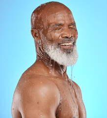 Fototapeta na wymiar Water splash, skincare and face of senior black man in studio isolated on a blue background. Cleaning, hygiene and retired elderly male from Nigeria bathing or washing for wellness and healthy skin.