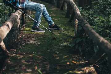 hiker with backpack sitting on old wood fence in the forest  while a rest. hiking and adventure concept.