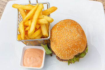 Hamburger and fries with pink sauce dip. Classic burger combo meal on white plate from top