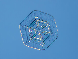 Snowflake on smooth gradient background. Macro photo of real snow crystal on glass surface. This is...