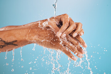 Black woman, water splash or washing hands on blue background in studio for hygiene maintenance, healthcare or wellness. Zoom, wet model or cleaning fingers for bacteria security or virus risk safety