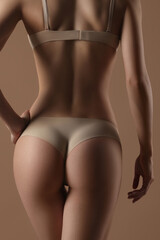Obraz premium Thin young woman in underwear on beige background