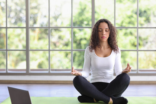 Sporty African American Woman Sit On Floor Practicing Mediate Yoga Watching Coach Training Video Online From Computer. Healthy Female Doing Exercise And Taking Lesson Distant Course At Home