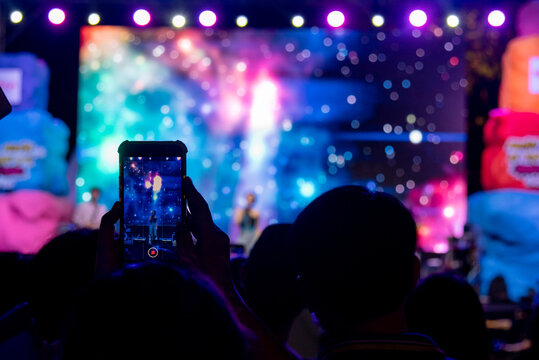 person using mobile smartphone taking photo festival music concert.