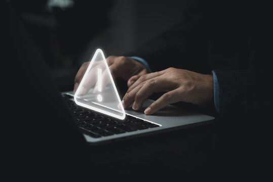 Businessman programmer, developer using laptop computer with triangle caution warning sign for notification error and maintenance concept.