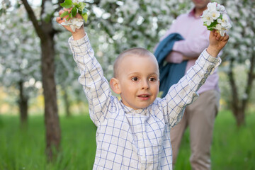 A happy child in a blooming spring garden rejoices, smiles.