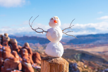 Tiny snowman on wooden post. Blurred Fiery Furnace sandstone landscape scenery in Arches National...