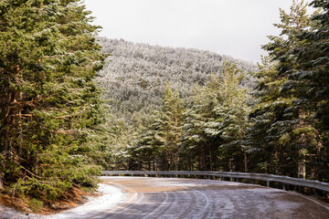 slightly snowy road in the mountains of the Sierra de Guadarrama in Madrid with the first snow of the year 2022