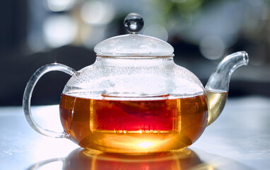 Tea, drink and fresh with a bag in a glass pot for drinking, refreshment or brewing on a table in...
