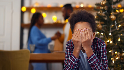 Sad, desperate little boy closing eyes during parents quarrel on christmas eve