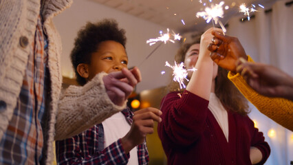 Happy family with friends celebrating christmas burning sparklers