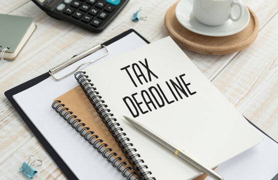 Tax Deadline text on notepad with calculator and cup coffee on wooden background