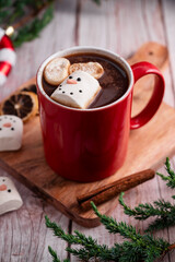 Obraz na płótnie Canvas Red mug with hot chocolate and melted marshmallow snowman, rustic wooden festive background
