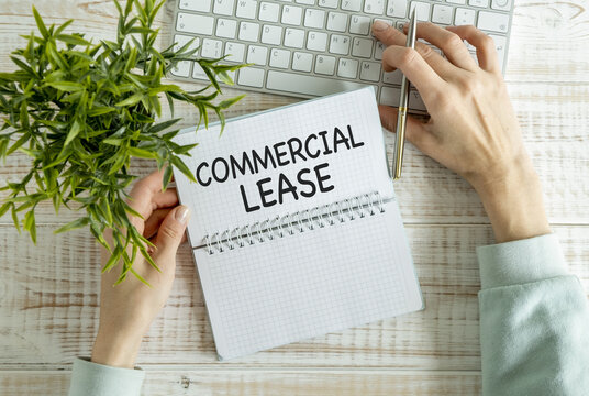 COMMERCIAL LEASE text on a notebook with clipboard and calculator on wooden background