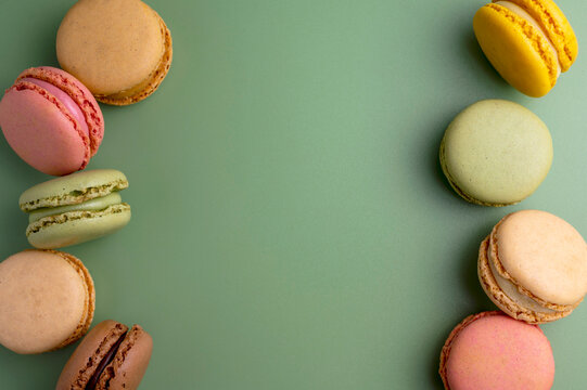 Macaroons colorful cookies. Macarons in bowl, french sweet dessert, top view, green background. Copy space.