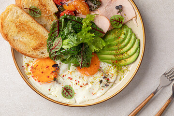 Portion of fried eggs breakfast with salad and avocado
