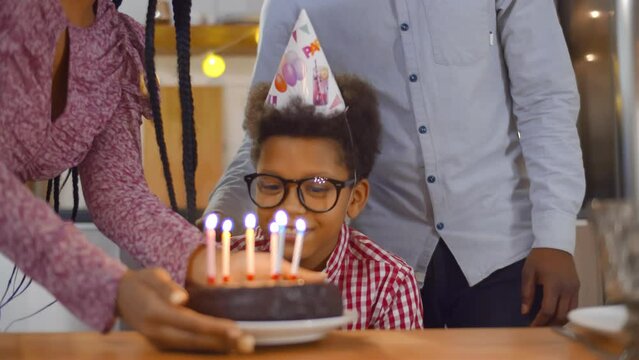 Close up of African-American mother and father congratulating preteen son holding birthday cake