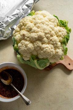 Whole cauliflower head with herbs and spices. Cooking process of roasted cauliflower, top view.