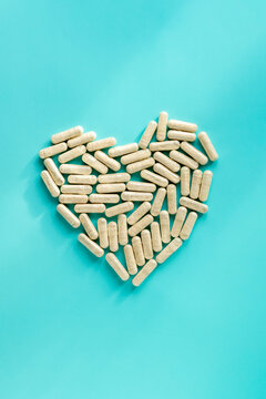 Pills in heart shape on blue background. Health care food supplements, vitamins and medicaments