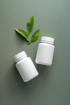 White pill bottles on green background. Health care food supplements, vitamins and medicaments