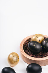 Eggs painted gold and black on white background. Overhead of nest containing egg. Minimal Easter concept with copy space for text.