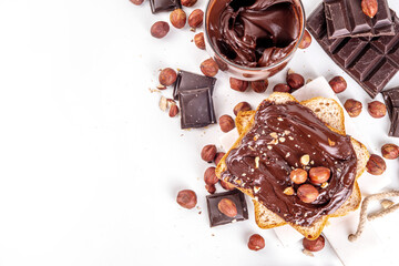 Bread with chocolate hazelnuts paste cream. Traditional american European sweet breakfast dope snack. Sandwiches with jar of chocolate nut cream, hazelnuts and chocolate slices, on white background
