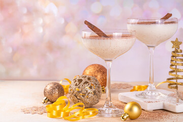 Eggnog Martini cocktail with cinnamon and nutmeg, with golden Christmas decorations and bokeh effect, copy space