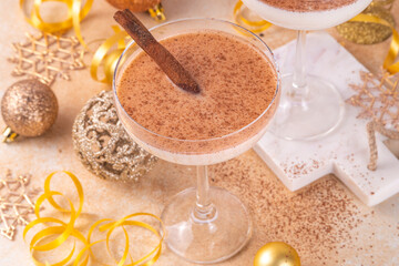 Eggnog Martini cocktail with cinnamon and nutmeg, with golden Christmas decorations and bokeh effect, copy space