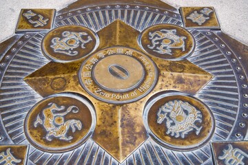 Closeup of a bronze medal on a Chinese highway, zero kilometer landmark