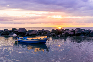 Fototapeta na wymiar boat in morning or evening sea with rock pier and amazing sunrise or sunset with nice clouds on background of landscape