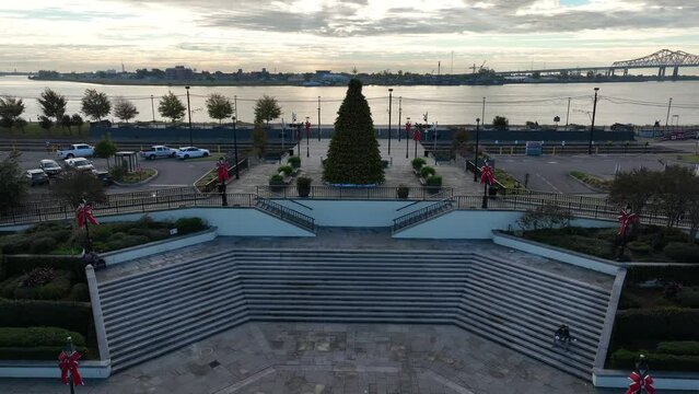 Sunset by river with decorated holiday Christmas Tree. Aerial push in toward water and bridge.